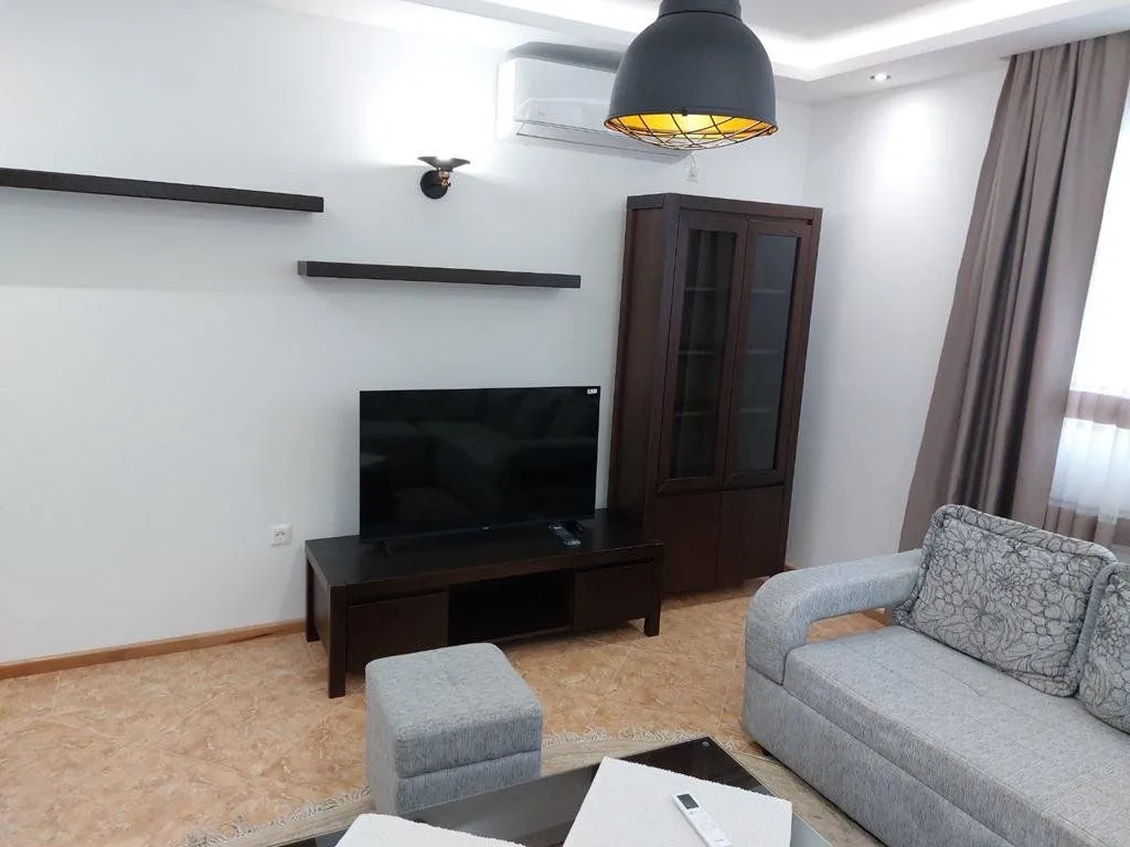 Living room with a sofa set, television, and wooden cabinet.