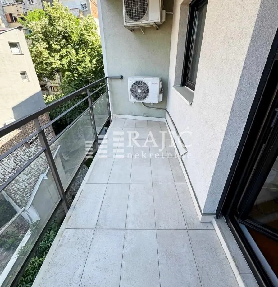 Small tiled balcony with a railing and air conditioning outdoor units.