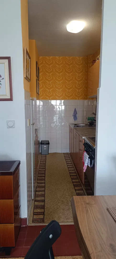 Manja kuhinja sa drvenim elementima i tapetama u narandžastoj boji.