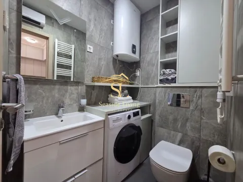Modernly equipped bathroom with a sink, toilet, and washing machine. - image 10