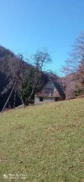Pogled na stari seoski objekat okružen prirodom i brdima. - image 7
