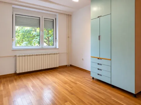 Prazna soba sa parketom, velikim prozorom i ugradnim ormarom. - image 5
