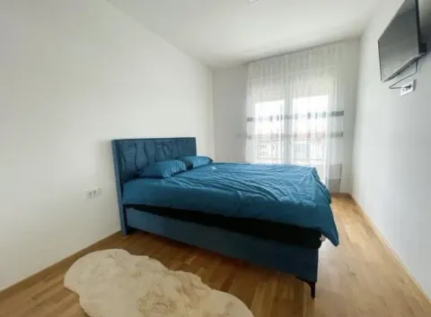Spavaća soba sa bračnim krevetom, drvenim podom i televizorom na zidu. - image 8