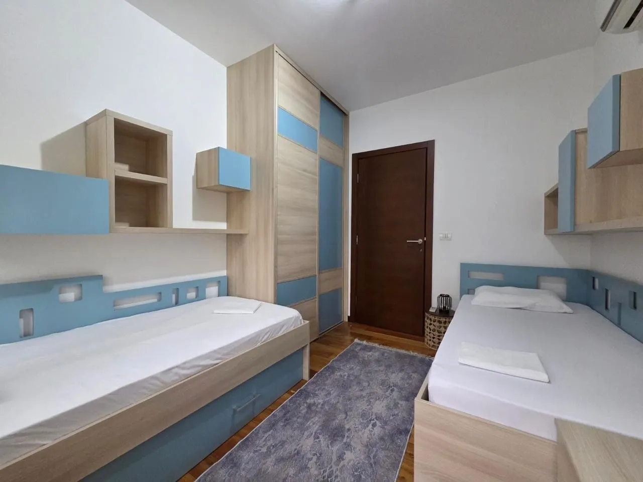 Children's bedroom with two single beds and a fitted wardrobe.