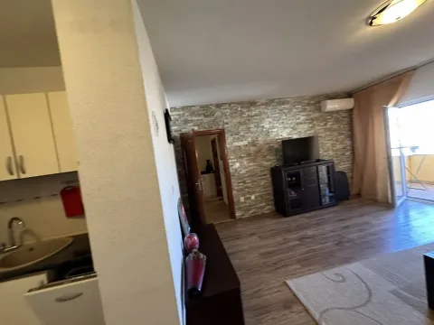 Dnevna soba sa zidom od dekorativnog kamena, televizorom i izlazom na terasu. - image 2