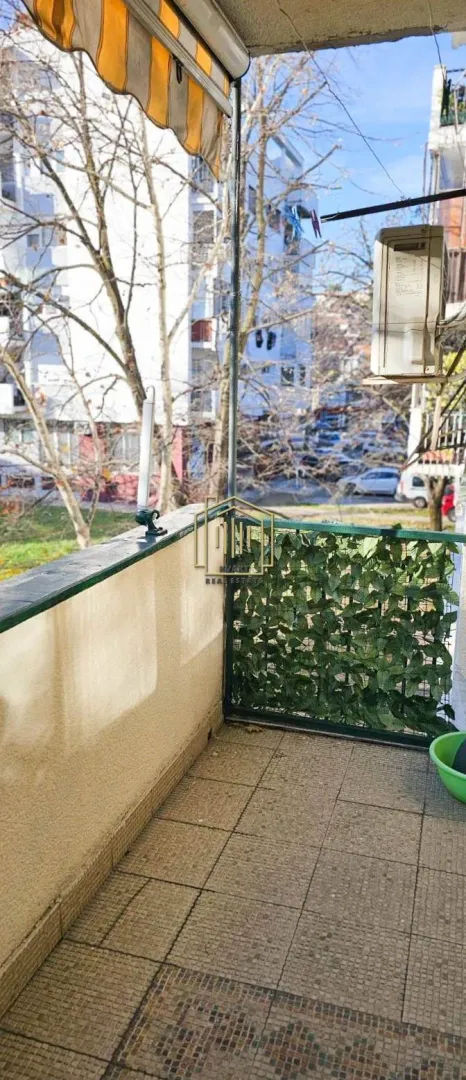 Natkrivena terasa sa pogledom na ulicu i drveće.