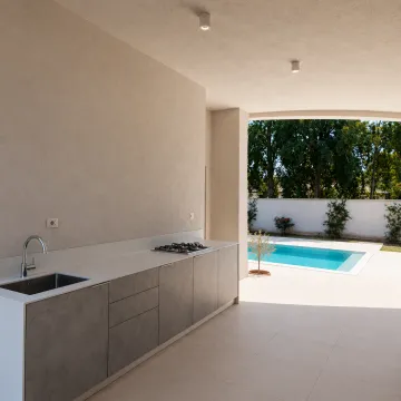 Covered patio area with an outdoor kitchen and a view of the swimming pool. - image 14