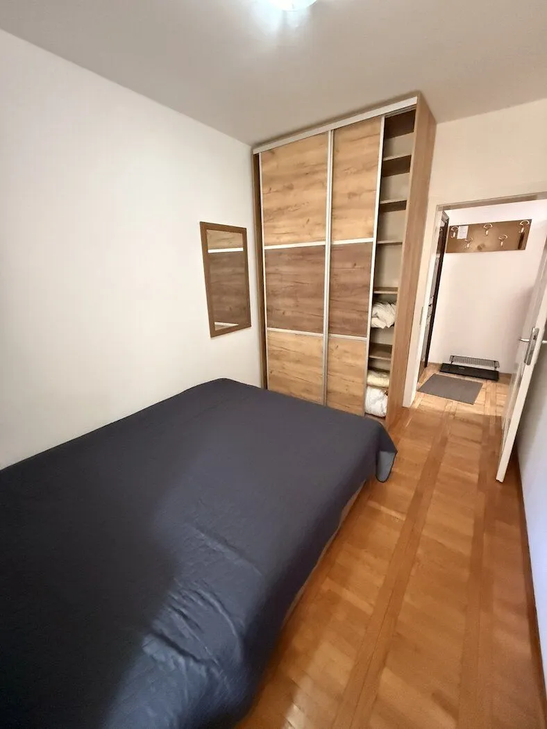 Small bedroom with a double bed, large wardrobe, and wooden flooring.