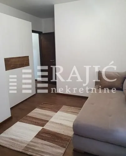 Furnished bedroom with a bed, wardrobe, and carpet.