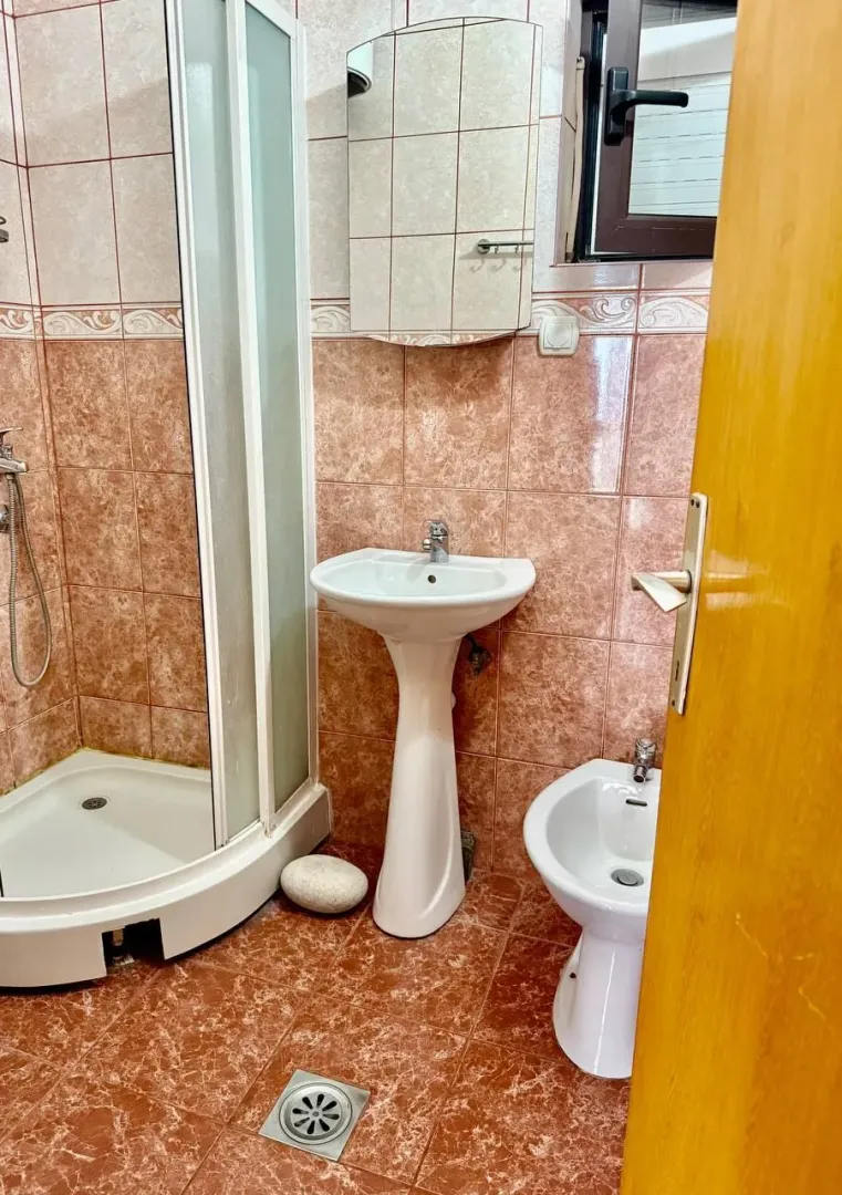 Manje kupatilo sa tuš kabinom, umivaonikom, bideom i pločicama.