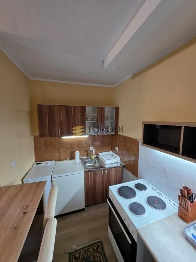 Compact kitchen with wooden cabinets, a sink, and an electric stove.
