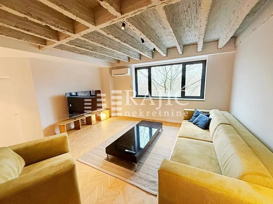 Living room with sofa, TV, and unique ceiling.