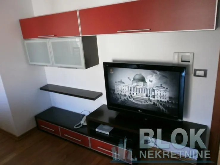 Living room with a TV and wall units.