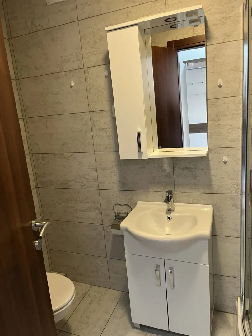A small bathroom with a white vanity sink and mirror cabinet.
