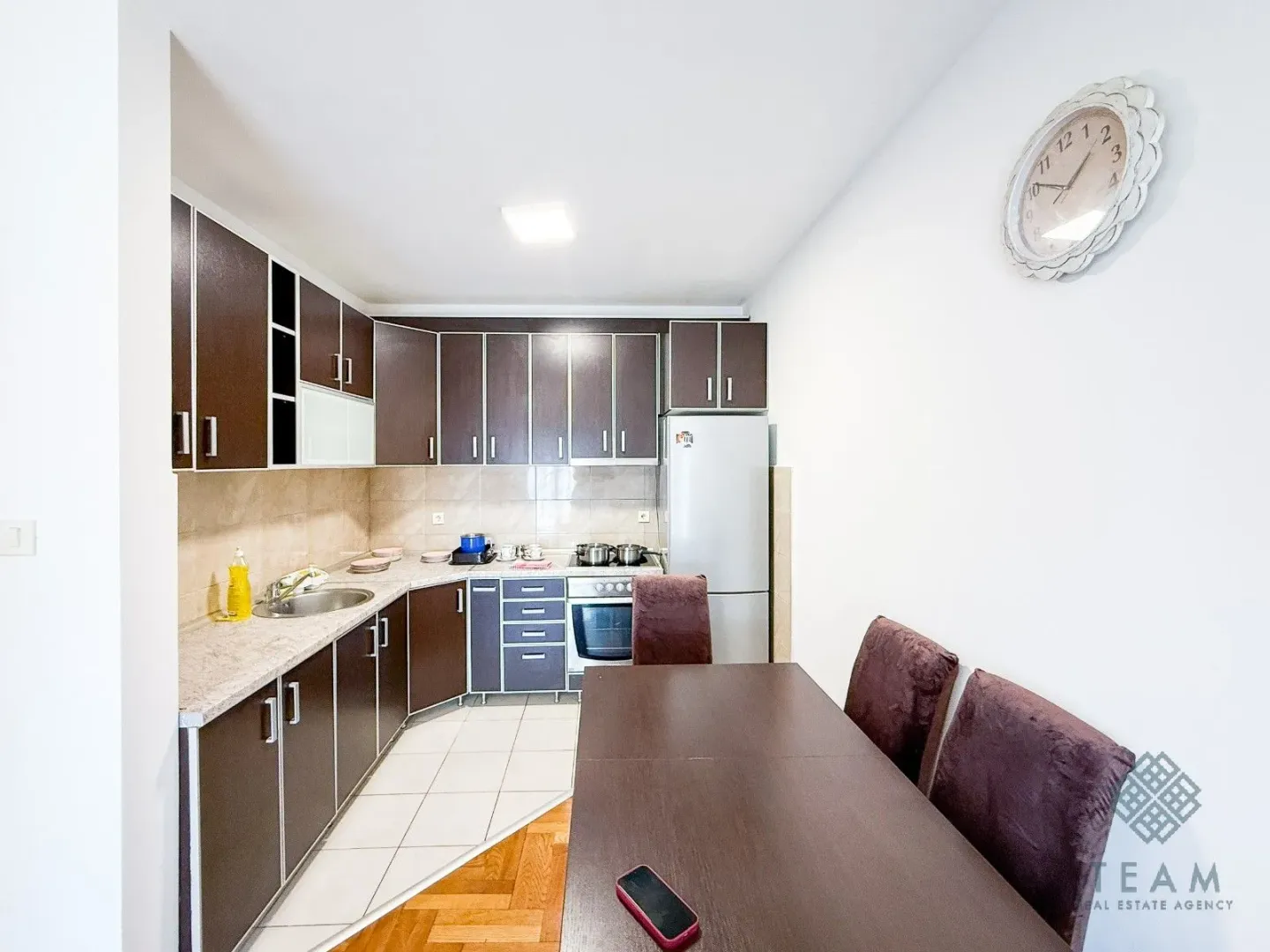 Kitchen with a dining area equipped with dark cabinetry and white goods.