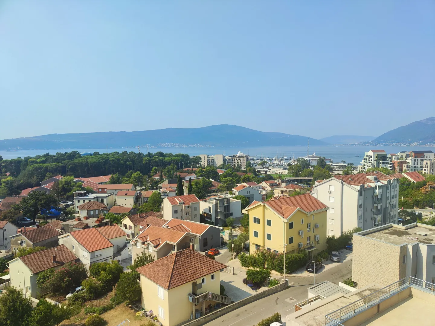 Pogled sa terase na naselje, more i planine u pozadini.