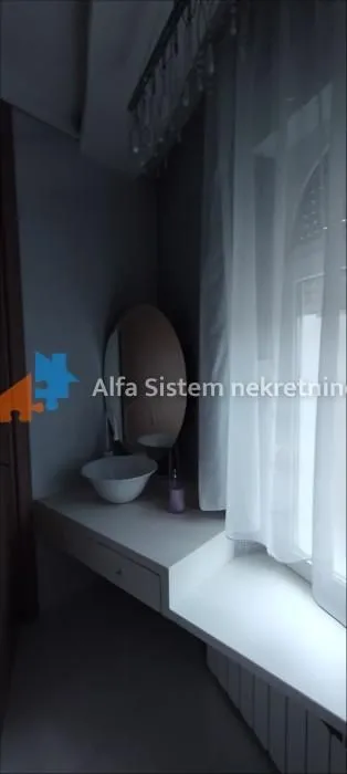 Kupatilo sa umivaonikom i ogledalom pored prozora.