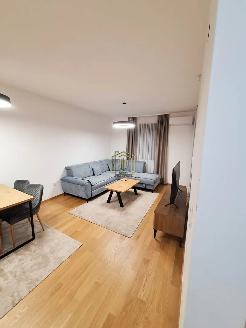 Living room with sofa, TV unit and dining table.