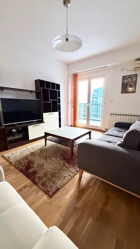 Dnevna soba sa garniturom, televizorom i izlazom na terasu.