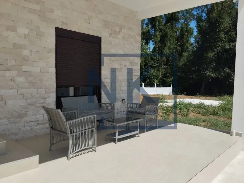 Covered terrace with seating furniture and a view of the yard.
