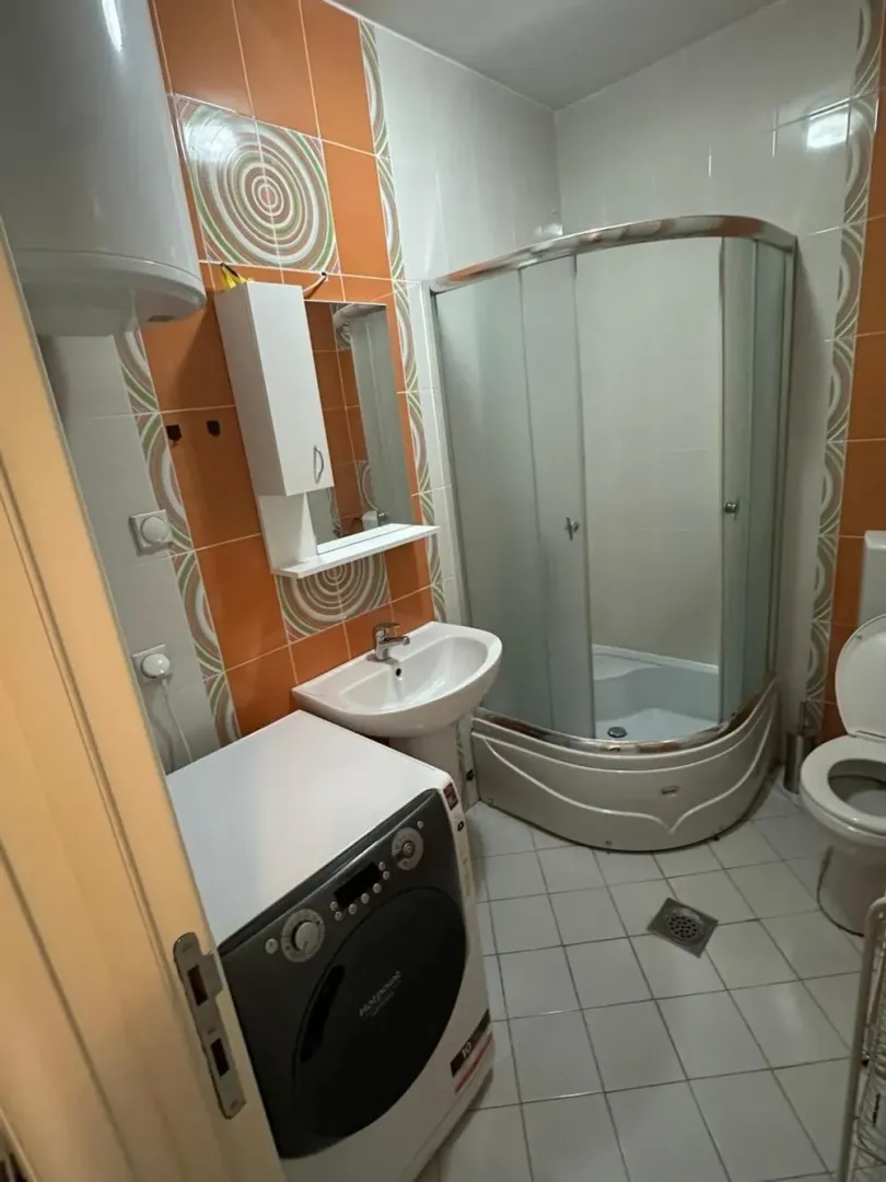 Bathroom equipped with a shower cabin, sink, toilet, and washing machine.