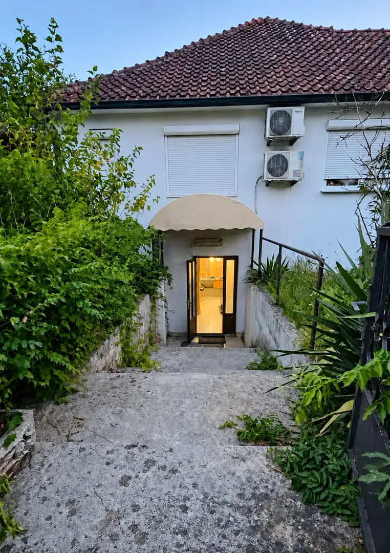 Ulaz u kuću sa stepeništem i zelenilom.