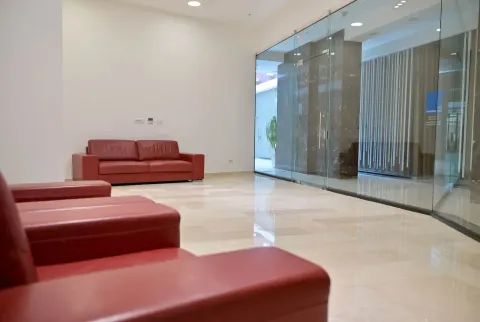 Spacious waiting area with red leather sofas and glass partitions. - image 4