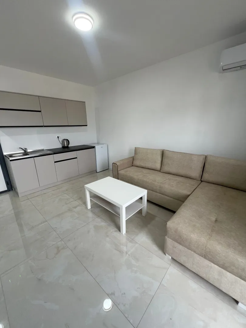 Living room with a sofa and a mini kitchen in light tones.