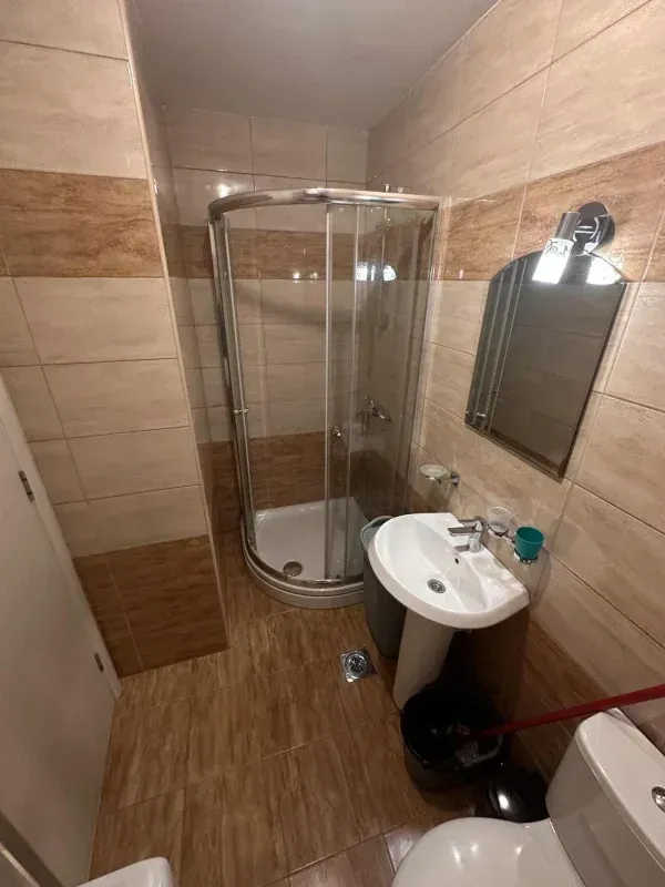 Smaller bathroom with a shower cabin, washbasin, and toilet.
