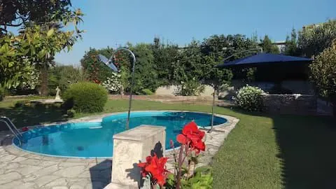 Yard of the house with a swimming pool, umbrella and landscaped lawn.