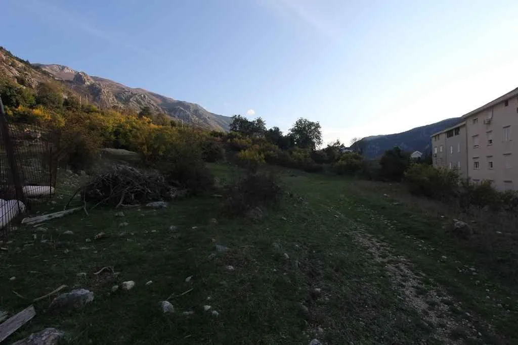 Zeleni plac pored stambene zgrade sa pogledom na brda.