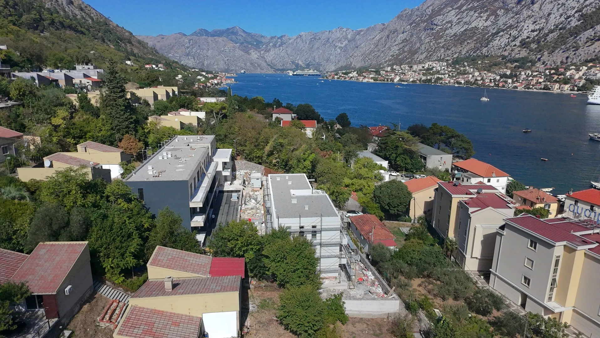 Pogled iz vazduha na naselje i obalu sa planinama u pozadini.
