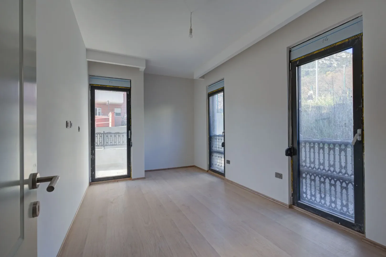Empty bright room with hardwood floors and balcony doors.