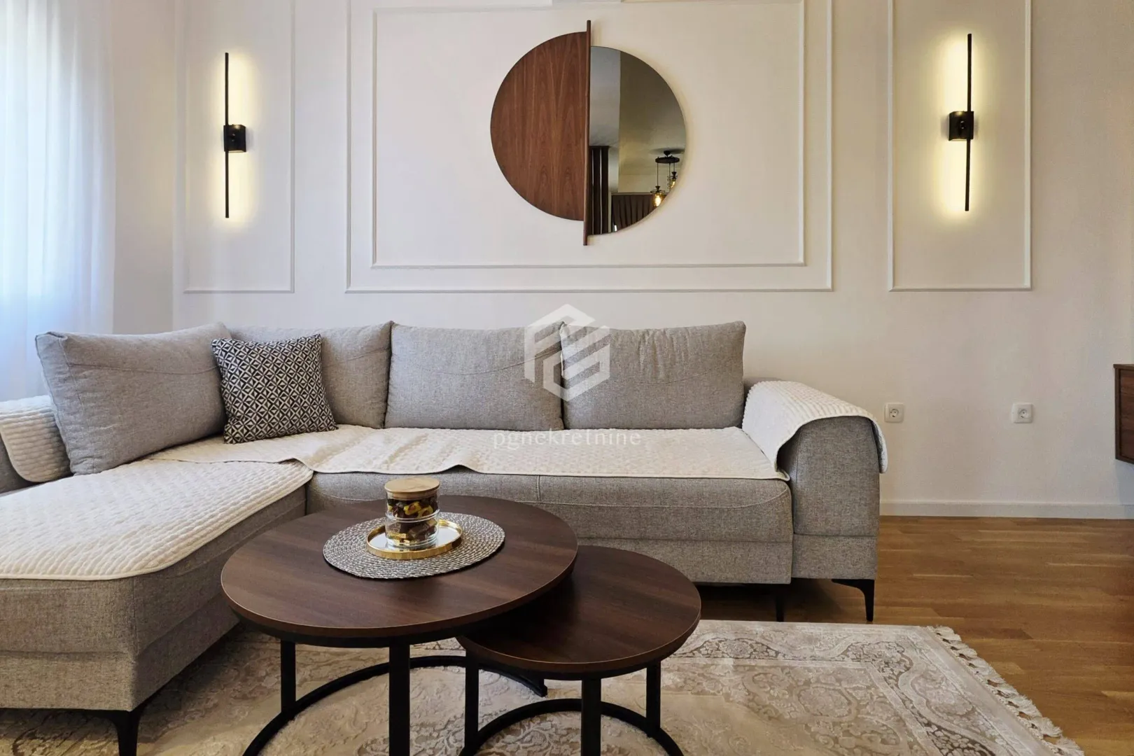 Living room with a sectional sofa, round coffee table, and decorative wall mirror.