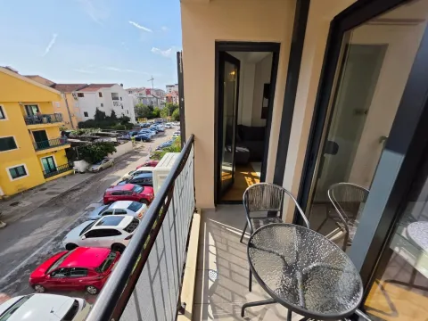 Namješten balkon sa stolom, stolicama i pogledom na ulicu i parking. - image 7
