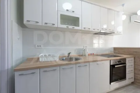Modern white kitchen with a wooden countertop and built-in appliances. - image 8