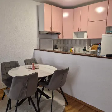 Dining area with a round table and chairs next to a kitchen with pink cabinets. - image 5