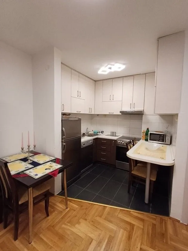 Kuhinja sa trpezarijskim stolom i ugradnim elementima.