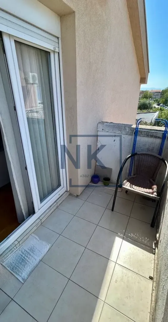 Manji popločani balkon sa stolicom i balkonskim vratima.