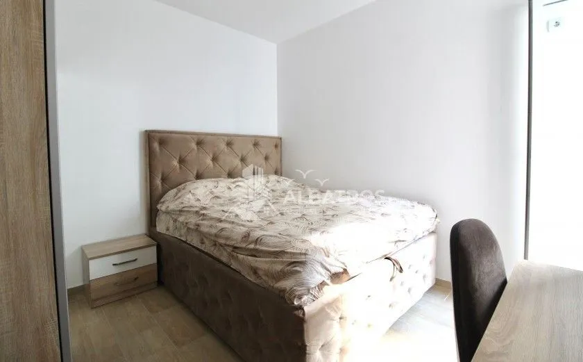 Namještena spavaća soba sa bračnim krevetom, noćnim stočićem i radnim stolom.
