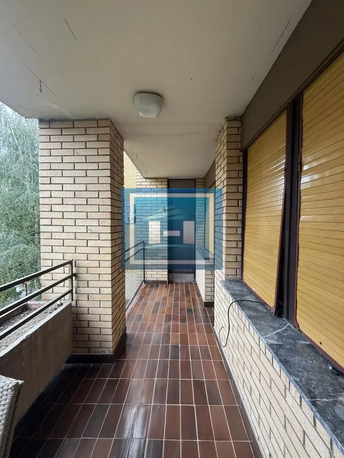 Long covered balcony with tiled flooring and brick pillars.