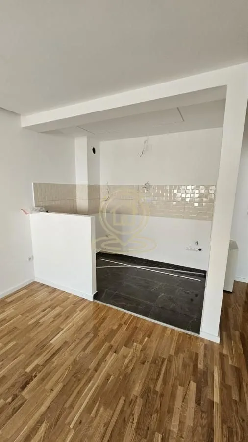 Nedovršeni kuhinjski prostor sa pločicama i drvenim podom u stanu.