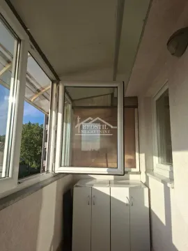 Zastakljeni balkon sa belim ormarićima i prozorom koji se otvara. - image 17