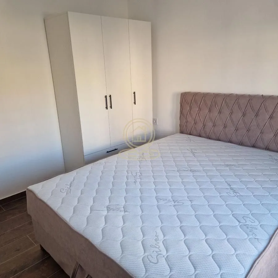 Nameštena spavaća soba sa bračnim krevetom i belim garderoberom.