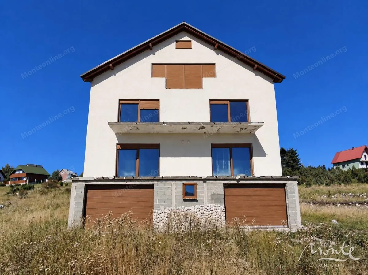 Pogled na spoljašnjost trospratne kuće sa garažama u prizemlju.