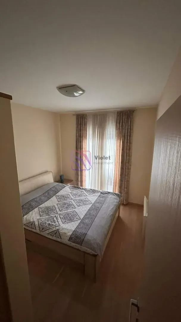 Spavaća soba sa bračnim krevetom, prozorom i zavjesama.