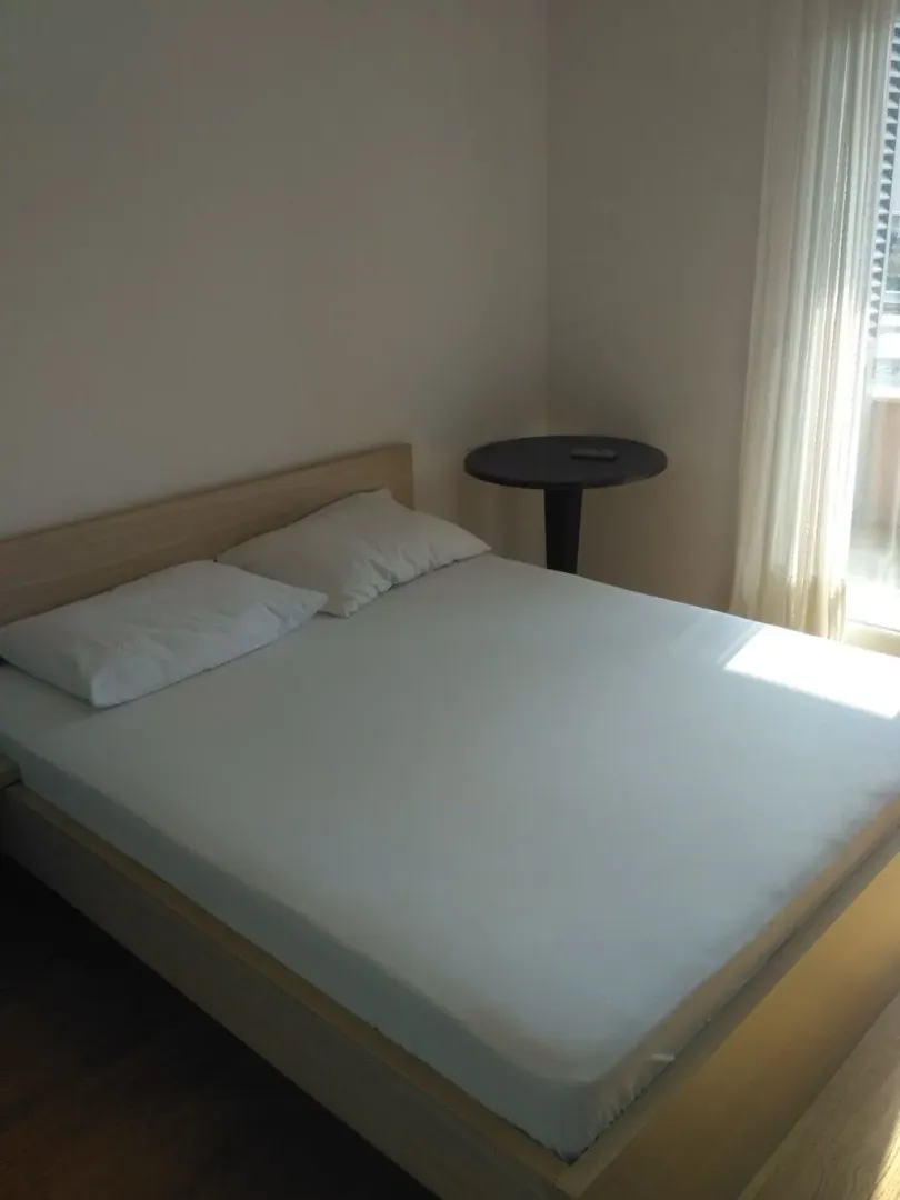 Bright bedroom with a double bed and a small table.