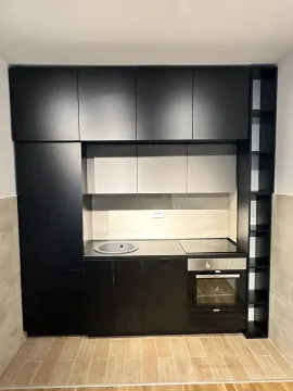 Modern black kitchen with built-in appliances and light tiles. - image 2