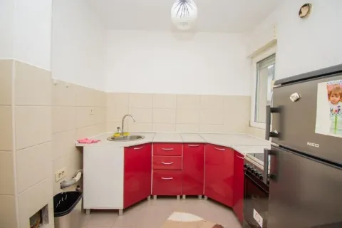A simple kitchen with red cabinets and a refrigerator. - image 5