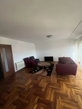 Prostrana dnevna soba sa parketom, crvenom garniturom i televizorom. - image 4